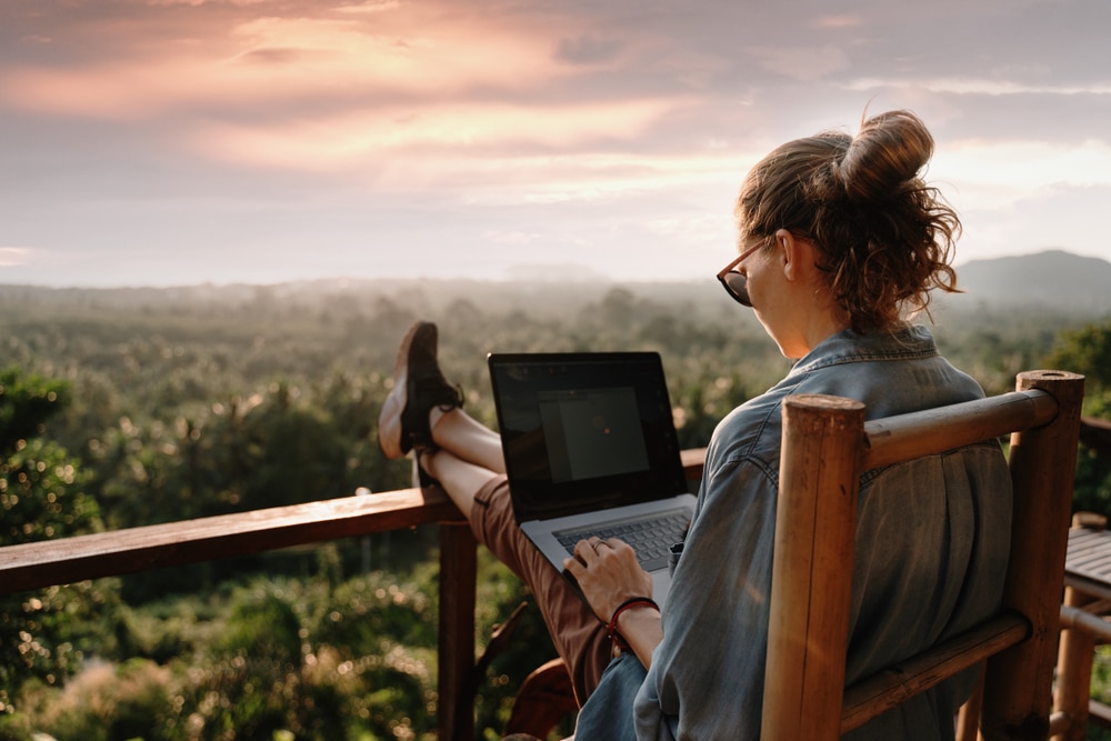 A back view of a girl using a laptop outdoors