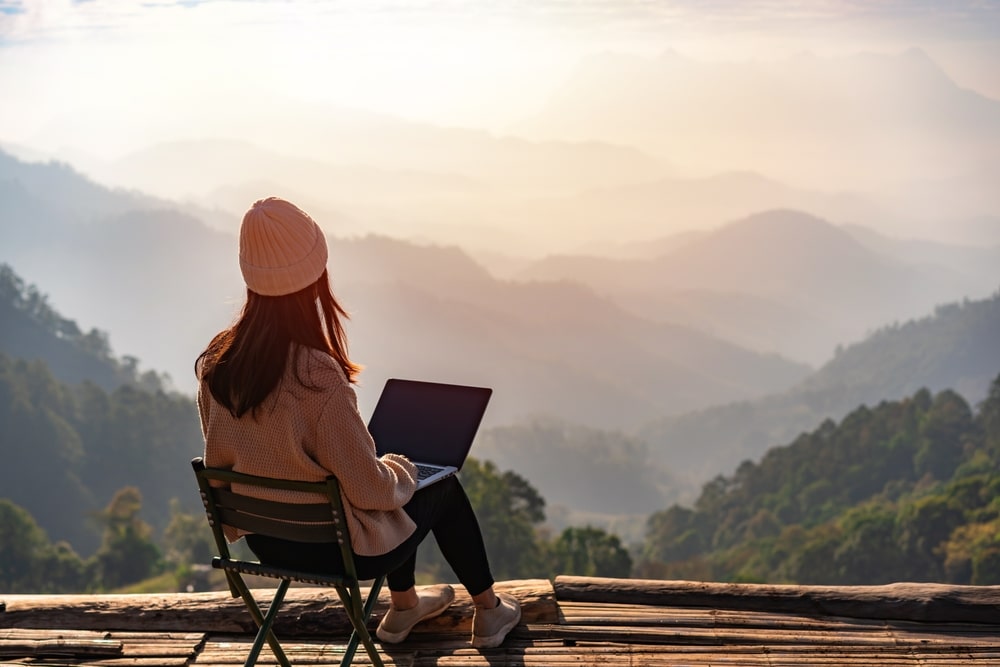 A view a girl using laptop outdoors in mountains