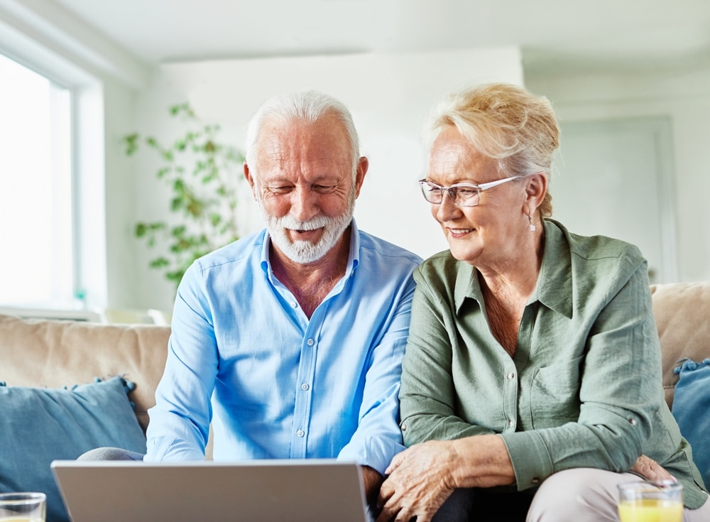 A view of an old couple sitting and using laptop