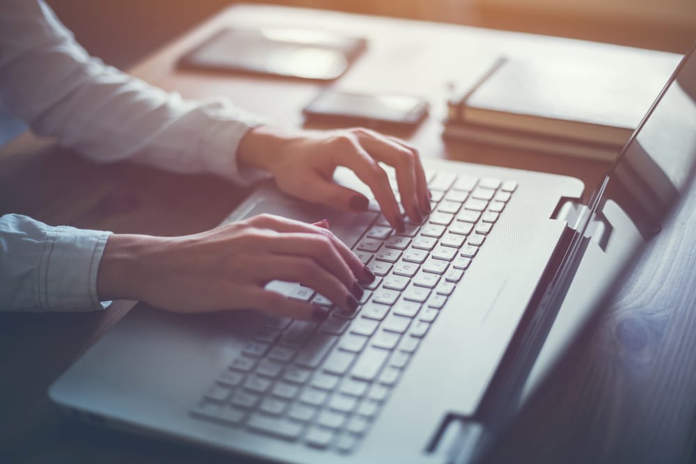 A view of hands writing on a laptop