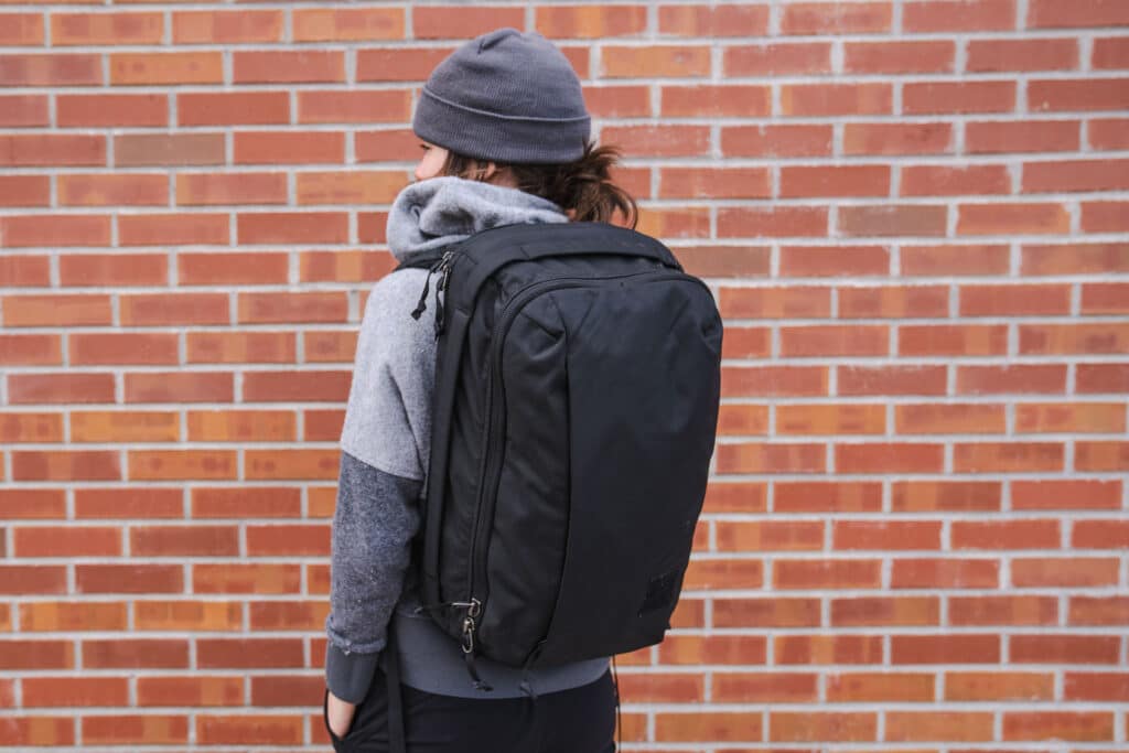 A girl carrying the Evergoods Civic Panel Loader Laptop Bag against the backdrop of a brick wall