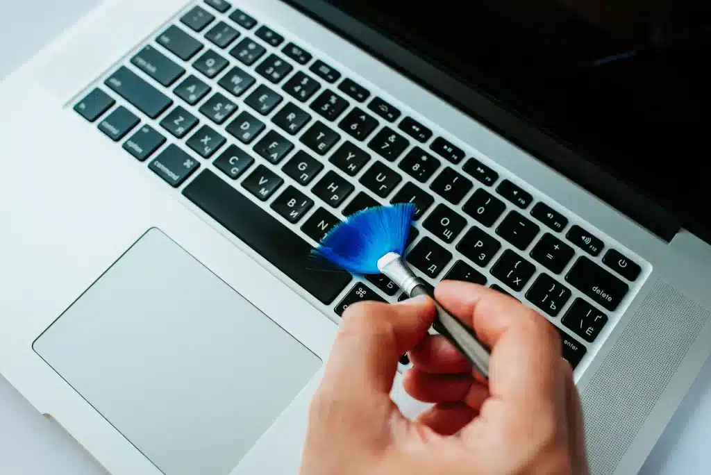 a person is cleaning the laptop keyboard with brush