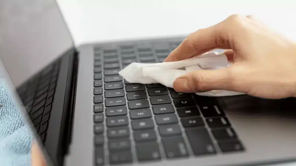 a person is cleaning the laptop with cloth