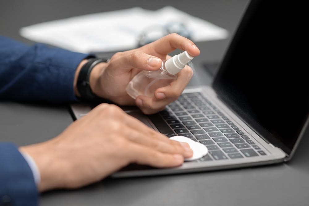 Unrecognizable Man In Suit Businessman Cleaning Laptop Keyboard With hydrogen peroxide 