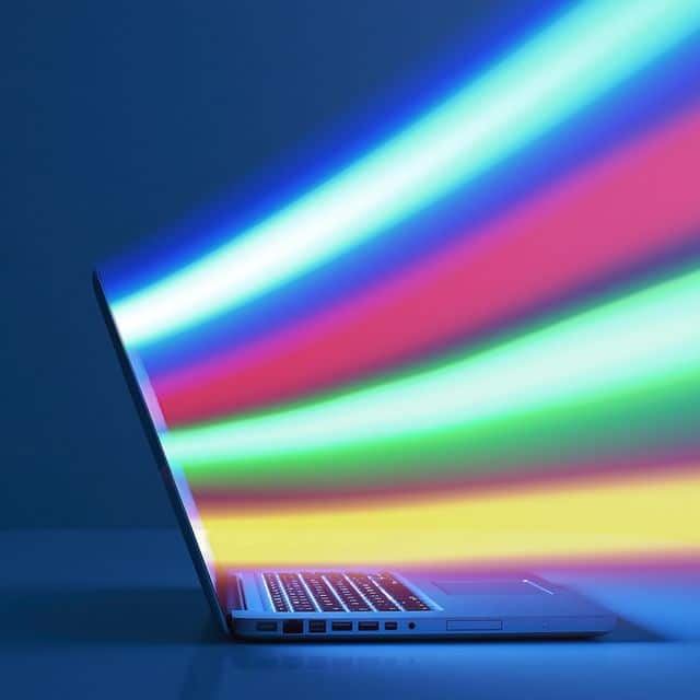 A side view of a laptop with colorful rays coming out of the screen