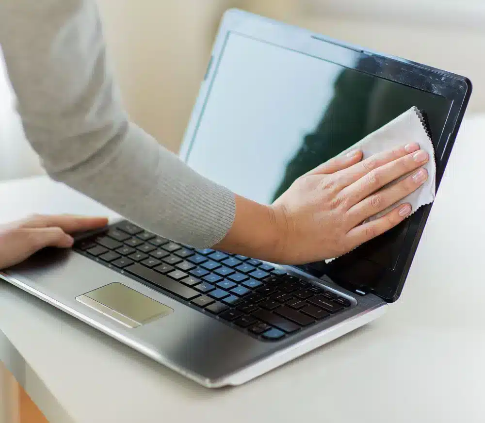 A view of a perosn cleaning the laptop screen with a cloth