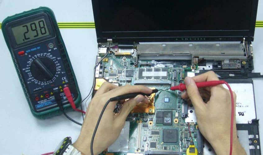 A view of a person checking the hardware of a laptop with a multimeter