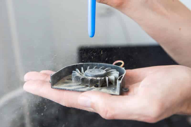 A view of a person cleaning a laptop fan dust