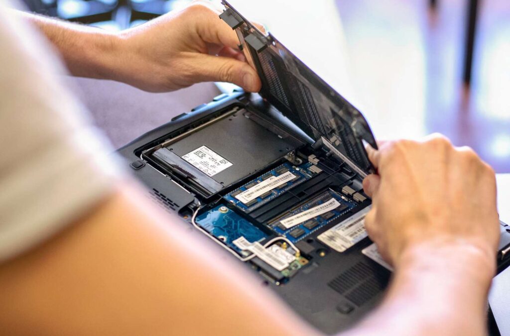 A view of a person opening the back of a laptop exposing the internal hardware