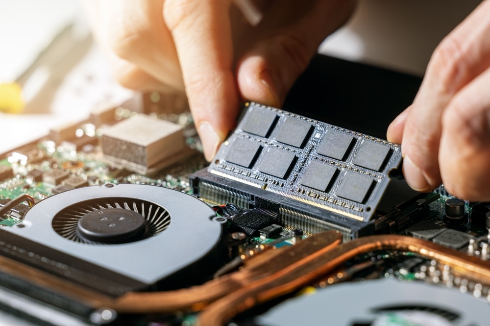 A view of a technician installing RAM to a laptop