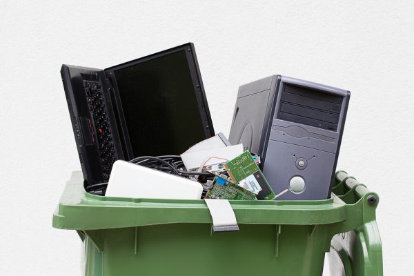 A view of laptop and cpu in a green trash can