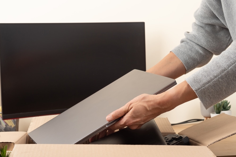 A view of hands disposing laptops inside a wooden carton