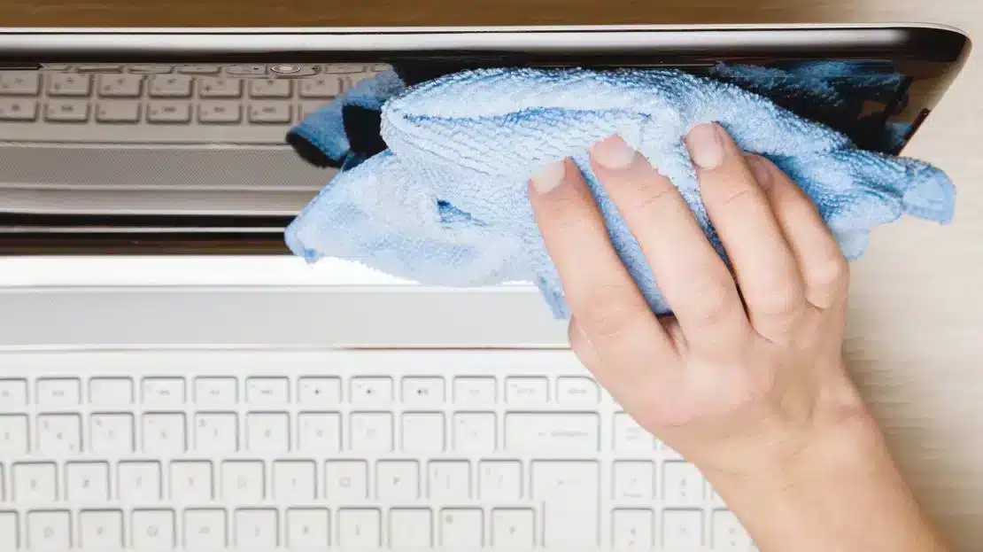 a person is cleaning laptop screen with micro fibre cloth