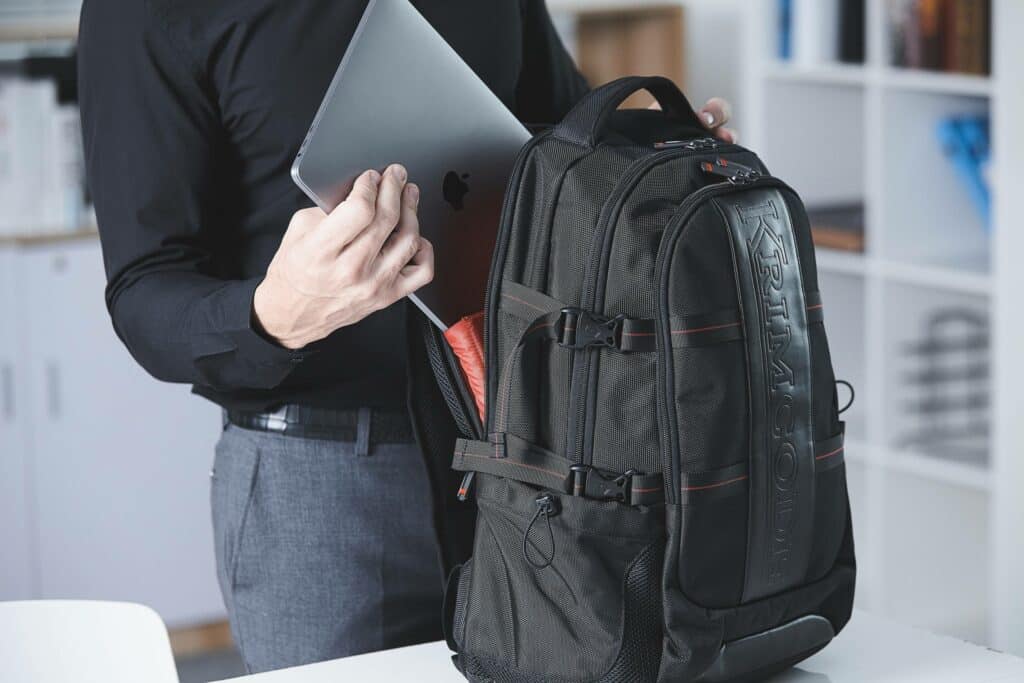 the person is putting the laptop in the laptop bag